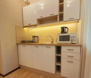 uma cozinha com armários brancos e um micro-ondas em Апартамент ГАЛИ em Pleven