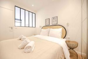 a white bedroom with a large bed with towels on it at Luxury Residence - Paris South in Montrouge