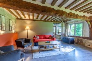 - un salon avec un canapé rouge et une table dans l'établissement Le Manoir du Perroy, à Saint-Wandrille-Rançon