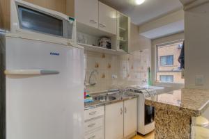 a kitchen with a white refrigerator and a sink at Ótimo apartamento no Centro mobiliado e com garagem in Curitiba