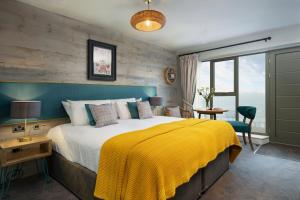 a bedroom with a large bed with a yellow blanket at The Old Success Inn in Sennen Cove