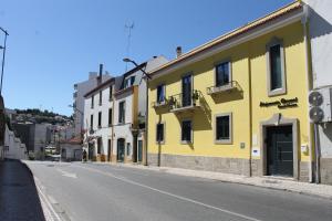 um edifcio amarelo no lado de uma rua em ALOJAMENTO GIRASSOL - Guest House - Quarto com casa de banho privativa em Castelo Branco