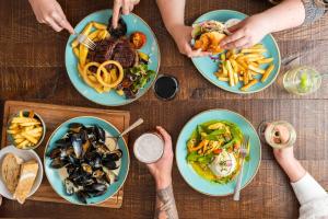 a group of people sitting around a table with plates of food at The Old Success Inn in Sennen Cove