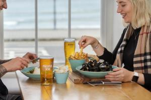 two people sitting at a table with food and drinks at The Old Success Inn in Sennen Cove