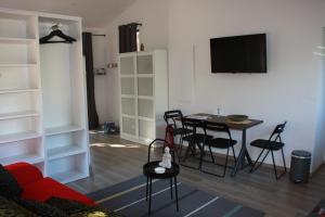 a living room with a table and chairs and a tv at Logis au milieu des pins in Le Puy-Sainte-Réparade