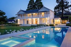 a large white house with a swimming pool in front of it at Te Mata House in Havelock North