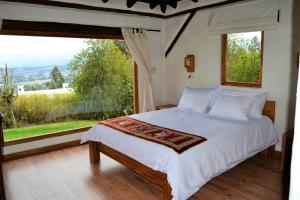 ein Schlafzimmer mit einem Bett und einem großen Fenster in der Unterkunft Ilatoa Lodge in Quito