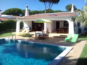a house with a swimming pool and a table and umbrella at Alsouk in Vilamoura