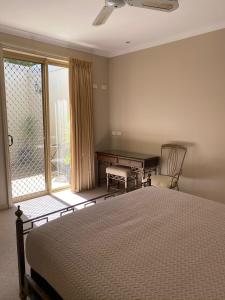 a bedroom with a bed and a desk and a window at Acacia Terraces in Echuca