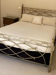 a bed with a metal frame and white sheets and pillows at Acacia Terraces in Echuca