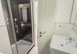 a white bathroom with a shower and a sink at Ferienwohnungen und Boardinghouse Heimbach in Lahr in Lahr