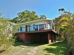 une maison avec un balcon au-dessus dans l'établissement Acacia Cottage at Hyams Beach, à Hyams Beach