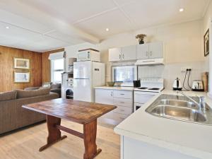 une cuisine et un salon avec une table et un canapé dans l'établissement Acacia Cottage at Hyams Beach, à Hyams Beach 15 autres photos