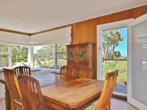 une salle à manger avec une table et des chaises en bois dans l'établissement Acacia Cottage at Hyams Beach, à Hyams Beach