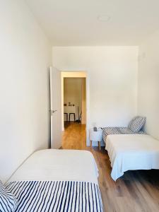 Habitación con 2 camas, paredes blancas y suelo de madera. en La Casa de los Álamos, en Málaga