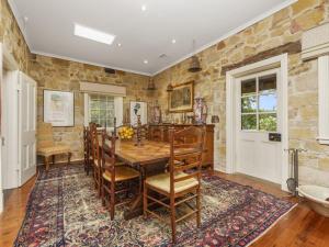 een eetkamer met een tafel en stoelen en een stenen muur bij Aylmerton House and Cottage for 14 Southern Highlands in Mittagong