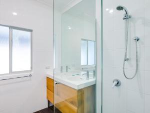 a white bathroom with a sink and a shower at Bimbadgen at Hyams Beach in Hyams Beach