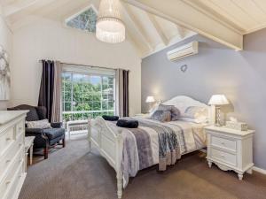 a bedroom with a bed and a chair and a window at Lou Lous Cottage Bowral Southern Highlands in Bowral