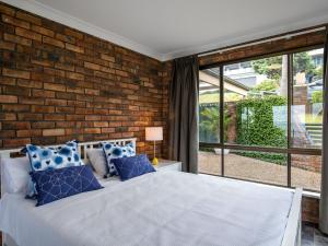 a bedroom with a brick wall and a bed with blue pillows at Jewel of Gerroa Gerroa in Gerroa