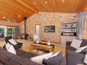 una sala de estar con 2 sofás y una pared de ladrillo en Netley Lodge for 10 Southern Highlands, en Fitzroy