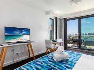 a hotel room with a bed and a desk with a television at Sebel Harbourside 301 Kiama in Kiama
