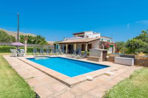 a swimming pool with chairs and a house at Black and white Cat Villa in Pollença