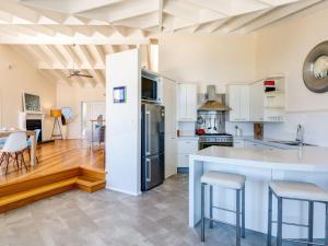 een keuken met witte kasten en een keukeneiland met barkrukken bij The Lookout at Gerroa in Gerroa