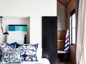 a bedroom with a bed with blue and white pillows at The Shed Gerroa in Gerroa