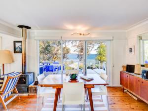Un comedor con mesa y sillas y una ventana. en The Shack at Palm Beach, en Sanctuary Point