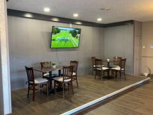 uma sala de jantar com mesas e cadeiras com uma televisão na parede em Conwy Valley Hotel em Conwy