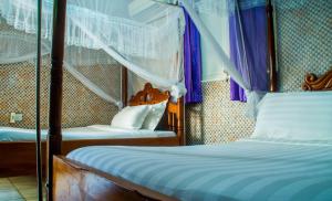 - une chambre avec 2 lits et des rideaux violets dans l'établissement Sandton Hotel Kasese, à Kasese