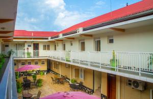 un balcón de un hotel con mesas y sombrillas en Sandton Hotel Kasese, en Kasese
