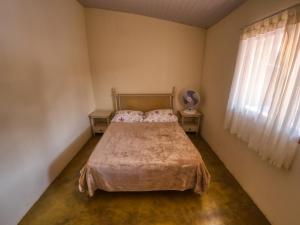 a bedroom with a bed and two tables and a window at Casa Ayurveda in Alto Paraíso de Goiás