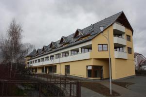 a yellow and white building with a black roof at Apartmán Edita in Velké Losiny