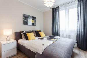 AbsyntApartments Old Town Wroclaw في فروتسواف: غرفة نوم بسرير كبير ومخدات صفراء وسوداء