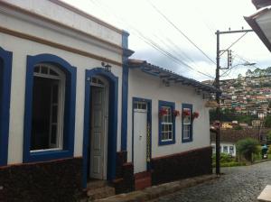 una casa azul y blanca con puertas azules en una calle en Pousada Ciclo do Ouro, en Ouro Preto