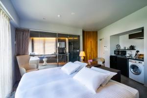 a bedroom with a large white bed and a kitchen at HOTEL PETIT SUITE SOGENJI ISHIMON in Naha