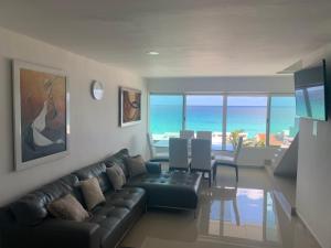 a living room with a couch and a dining room with the ocean at Penthouse frente al mar in Cancún