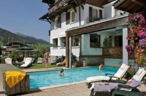 a group of people in a swimming pool next to a house at Hôtel Le Sporting in Morzine