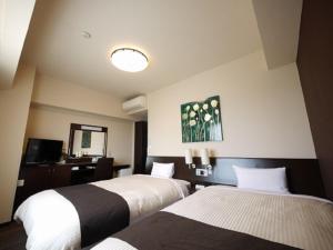 a hotel room with two beds and a mirror at Hotel Route-Inn Shimodate in Chikusei