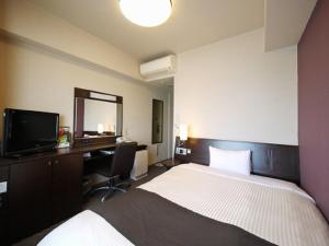 a bedroom with a bed and a desk and a television at Hotel Route-Inn Shimodate in Chikusei