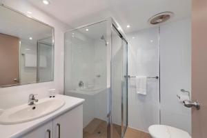 a white bathroom with a sink and a shower at Don Pancho Beach Resort in Bargara