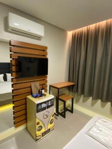 a room with a tv and a table and a bed at Absolut Confort Suites in Atalaia Velha