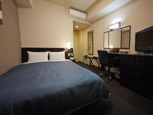 水戸市にあるホテルルートイン水戸県庁前のベッド、デスク、テレビが備わるホテルルームです。