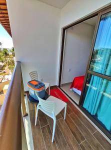 a balcony with a table and a chair and a window at Manawa Beach Flats Prime in Porto De Galinhas