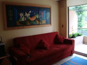 un sofá rojo en una sala de estar con una pintura en Departamento Reñaca Torremolinos XII, en Viña del Mar