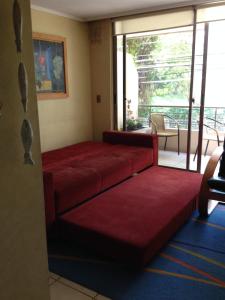 una sala de espera con sofás rojos y un balcón en Departamento Reñaca Torremolinos XII, en Viña del Mar