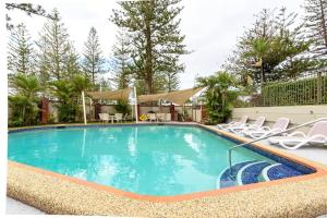 a swimming pool with chairs and a table and a building at Main Beach Waterfront Apartment in Gold Coast