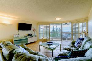 a living room with a couch and a tv at Main Beach Waterfront Apartment in Gold Coast