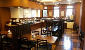 un restaurante con mesas y sillas de madera y un bar en Hotel Route-Inn Towada, en Towada
